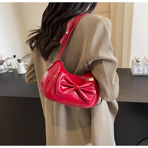 Detail showing the glossy red patent leather finish and large bow on the shoulder bag