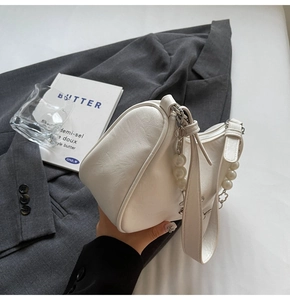 Detail of cream white half-moon bag with pearl metal chain and textured PU leather