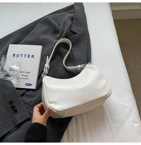 Close-up of minimalist white hobo bag with natural faux leather texture on grey suit fabric