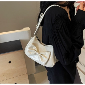 Close-up of creamy white glossy shoulder bag featuring large decorative 3D bows