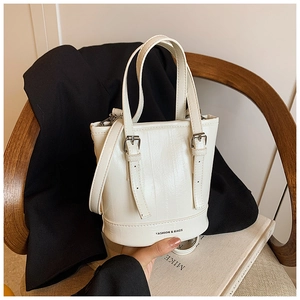Detail of white leather bucket bag with FASHION & BAGS text on a wooden chair
