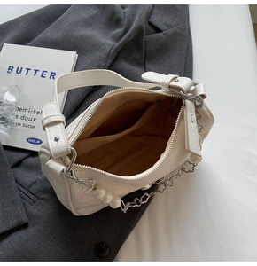 Detail of white underarm bag showing interior brown lining and floral pearl chain