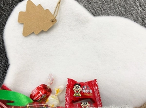 Close-up of white felt bone-shaped ornament with a rustic kraft paper tree tag and jute twine