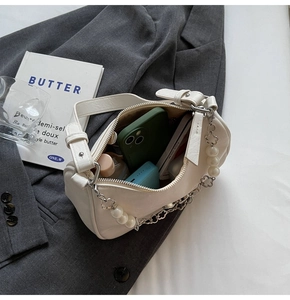 Spacious interior of a white pleated shoulder bag showing daily essentials and phone