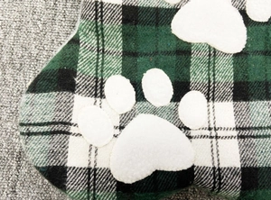 Detail of plaid Christmas stocking with white paw print applique and soft fabric texture
