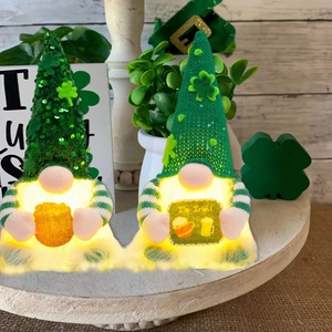Pair of lighted St. Patrick's Day gnomes with green sequins on a wooden tray