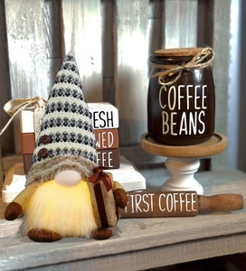 Close-up of a glowing coffee gnome doll with a white LED beard and a knit hat decoration