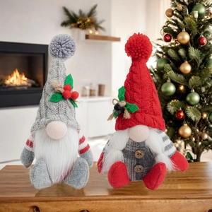 Detail of red and grey knitted Christmas gnomes with berries by a warm fireplace