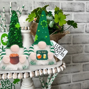 St. Patrick's Day gnomes featuring green sequins and shamrocks on a rustic display stand