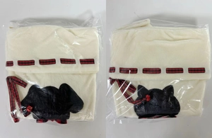 Detail of cream plush Christmas stocking with black cat patch and red plaid bow decoration