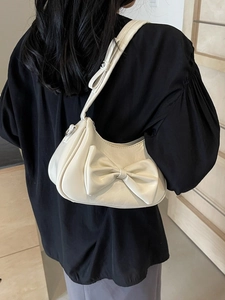 Chic beige underarm bag with large bow detail and sleek crescent shape for women