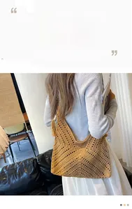 Gros plan sur la texture tressée et le gland d'un sac cabas en paille marron naturel