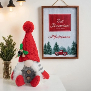 Detail of a handmade Christmas gnome with a red knit hat and wooden buttons decoration