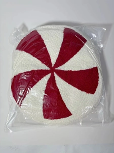 Detail shot of a round peppermint candy plush pillow packaged in a clear protective plastic bag