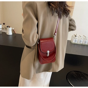 Détail du sac bandoulière rouge brillant avec fermoir rotatif argenté et lanière