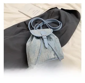 Détail d'un sac à dos en jean à paillettes bleu clair avec fermeture à cordon argentée