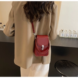 Gros plan sur l'élégant mini sac en cuir brillant bordeaux avec fermoir en métal argenté