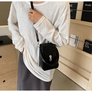 Détail d'un mini sac à bandoulière noir avec fermoir en métal argenté et fine lanière