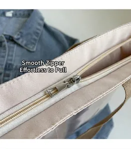 Close-up of smooth silver metal zipper and brown handles on a beige nylon tote bag