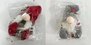 Detail of red and gray knitted Christmas gnomes with holly leaves in clear plastic packaging