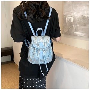 Vue détaillée du mini sac à dos bleu clair à paillettes avec bretelles en cuir et détails
