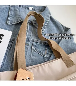 Detail of the thick khaki shoulder strap and cute biscuit pendant on a nylon tote bag