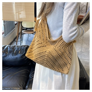 Détail du sac cabas en paille tressée avec pompons bohèmes et grand design en filet