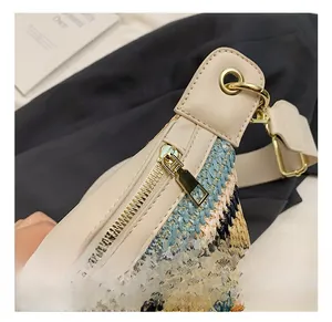 Close-up of woven crossbody bag with tricolor pattern and golden zipper details