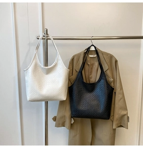Detail of black and white woven tote bags showing fine checkerboard texture on metal hanger