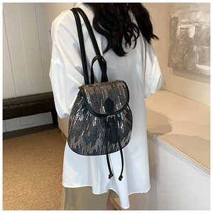 Détail d'un mini sac à dos en denim avec paillettes argentées et finitions en cuir