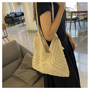 Gros plan sur un sac à bandoulière au crochet beige avec textures géométriques et pompons