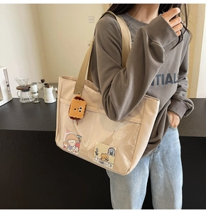 Detail of beige nylon tote bag with transparent PVC pocket and a cute biscuit plush charm