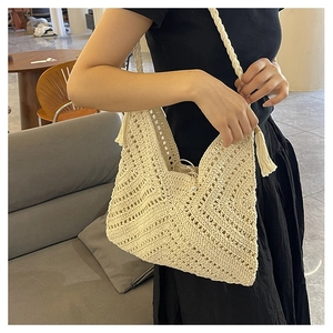 Gros plan d'un sac à bandoulière tissé avec pompons et bandoulière tressée sur mannequin