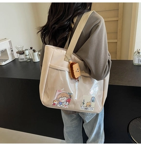 Detail of off-white canvas tote bag with transparent PVC pocket and cute biscuit plush charm
