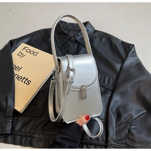 Détail d'un sac argenté géométrique avec fermoir métallique et bandoulière réglable