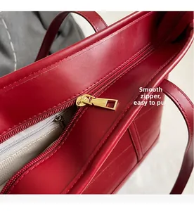Detail shot of smooth golden zipper and premium lining on burgundy leather tote bag