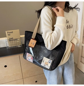 Close-up of black nylon tote bag with clear PVC pocket and cute plush bear charm