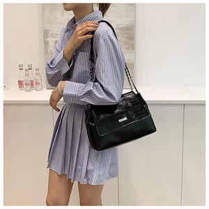 Detail of glossy black crinkled leather shoulder bag with silver chain and metal clasp