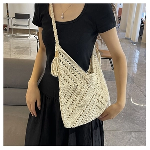 Détail de la texture tissée ajourée et pompons sur un sac à bandoulière en crochet