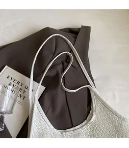 Detailed close-up of woven texture and thin shoulder strap on this white tote bag