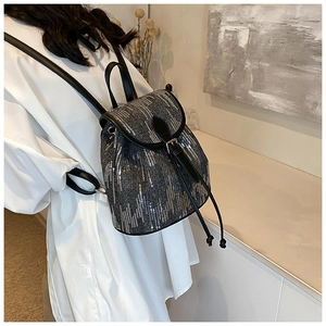 Mini sac à dos en denim avec paillettes argentées et lanières en cuir porté par un modèle