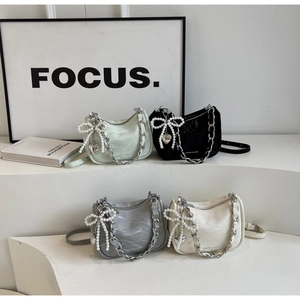 Detail of four pleated half-moon bags with silver chains and pearl bow charms