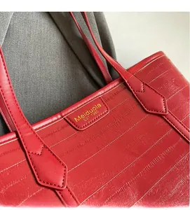 Detail of red crocodile texture tote bag with gold brand logo and embossed finish
