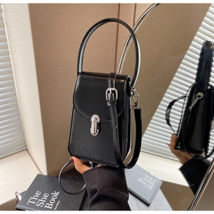 Détail du mini sac en cuir verni noir avec boucle argentée et reflet dans le miroir
