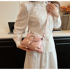 Glossy pink crossbody bag with silver heart buckle shown on model in a stylish setting