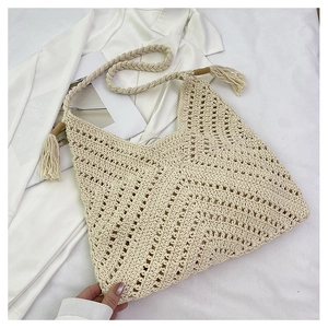 Détail macro du sac fourre-tout beige au crochet avec texture ajourée et pompons