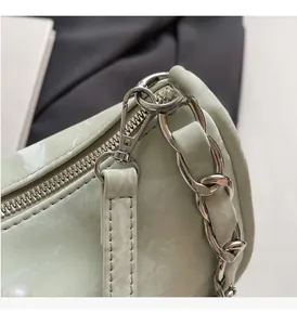 Macro detail of high-shine silver metal hardware and light green faux leather texture