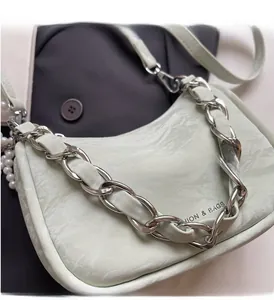 Detail of mint green leather handbag featuring metal chain strap and pearl accessory