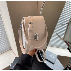Détail d'un sac bandoulière blanc crème avec fermoir tournant argenté et bandoulière