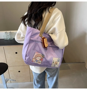 Detail of purple nylon tote bag featuring transparent PVC pocket and plush charm accessory